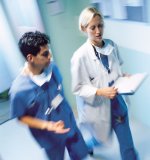 Female Physician and male Nurse walking in a Hospital hallway and talking. 